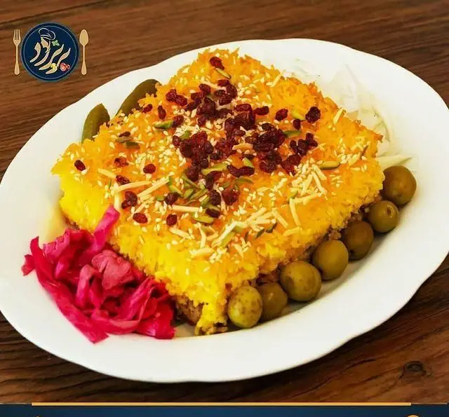 عکس با کیفیت از ته‌چین زعفرانی لذیذ و مجلسی رستوران کترینگ پریزاد با تزیین زرشک، خلال پسته و کنجد، به همراه زیتون و ترشی.