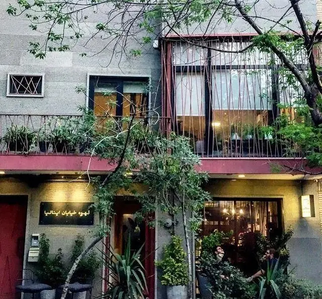 نمای بیرونی دنج کافه قهوه پیانسا با بالکن سرسبز، گیاهان آویزان، و پنجره‌های بزرگ در طبقات، فضایی جذاب و دعوت‌کننده.