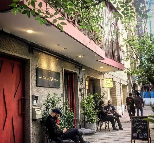 نمای جلوی کافه قهوه پیانسا، با تابلوی "قهوه خیابان ایتالیا"، مشتریان در حال لذت بردن از قهوه در فضای باز و محیط شهری.