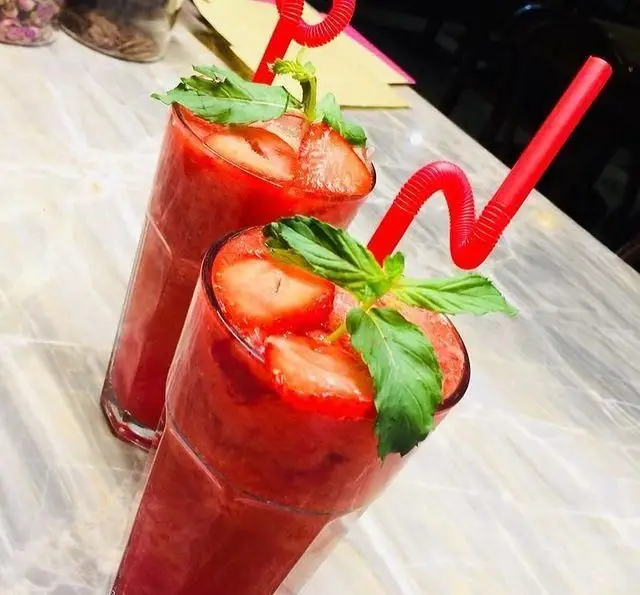 لذت نوشیدن دو اسموتی توت فرنگی قرمز و خوش‌طعم با تزئین نعناع و توت فرنگی در فضایی دلنشین و شیک.