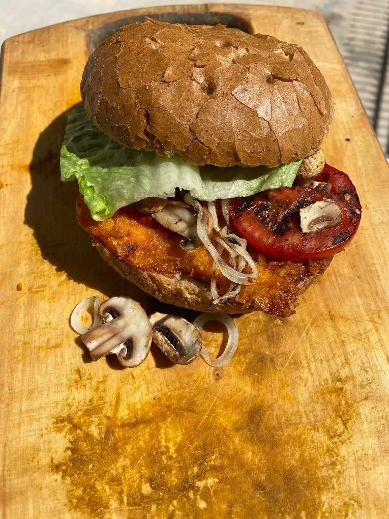 برگر گیاهی سالم و رژیمی رستوران رژیمی گیاهی تیم فیت. شامل نان قهوه‌ای، کاهو، گوجه کبابی، قارچ و پیاز روی تخته چوبی. غذای وگان ایده‌آل.