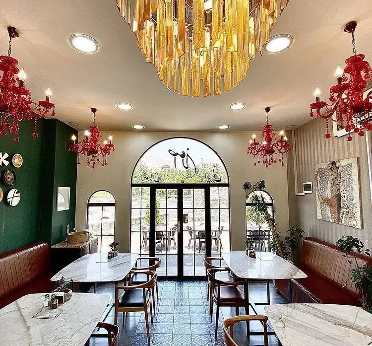 نمای داخلی رستوران اصلان: دکوراسیون لوکس و مدرن با میزهای مرمری، لوسترهای کریستالی قرمز و طلایی، صندلی چوبی و فضای دلنشین برای صرف غذا.