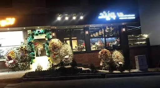 نمای بیرونی رستوران ایتالیایی ویند در شب، مزین به نورپردازی و تزیینات افتتاحیه شیک، شامل طاق بادکنک و گل‌آرایی باشکوه.