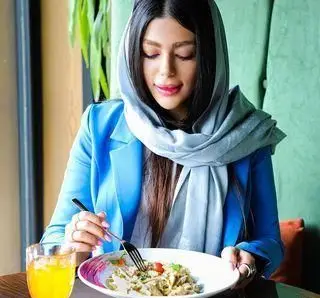 زنی در رستوران ایتالیایی ویند مشغول خوردن پاستای لذیذ. تجربه ای دلنشین از طعم های اصیل ایتالیایی در فضایی آرام.