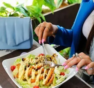 در رستوران ایتالیایی ویند، بانویی خوشحال در حال میل کردن سالاد مرغ تازه و خوشمزه با سس مخصوص است. تجربه‌ای دلنشین و خاطره‌انگیز برای ناهار یا شام.