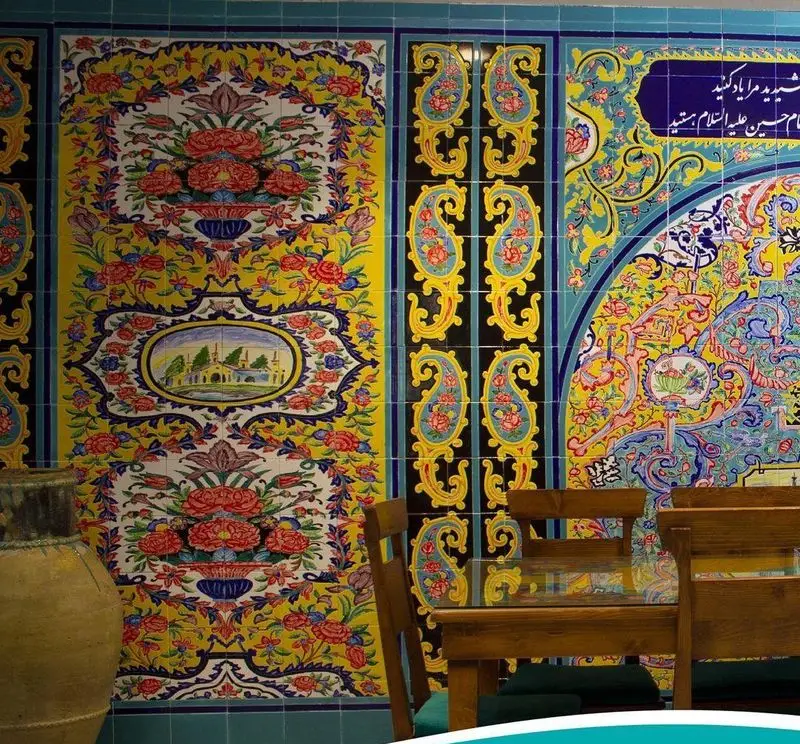 دیوارپوش کاشی‌کاری سنتی رستوران مرشد سعادت آباد با طرح‌های زیبای گل و بوته و منظره‌ای دلنشین، فضایی اصیل و ایرانی.