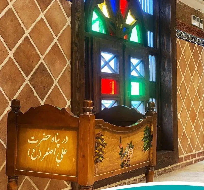 معماری و دکوراسیون سنتی و چشم نواز رستوران مرشد سعادت آباد با پنجره ارسی رنگی، گهواره چوبی و کاشی‌کاری ایرانی.