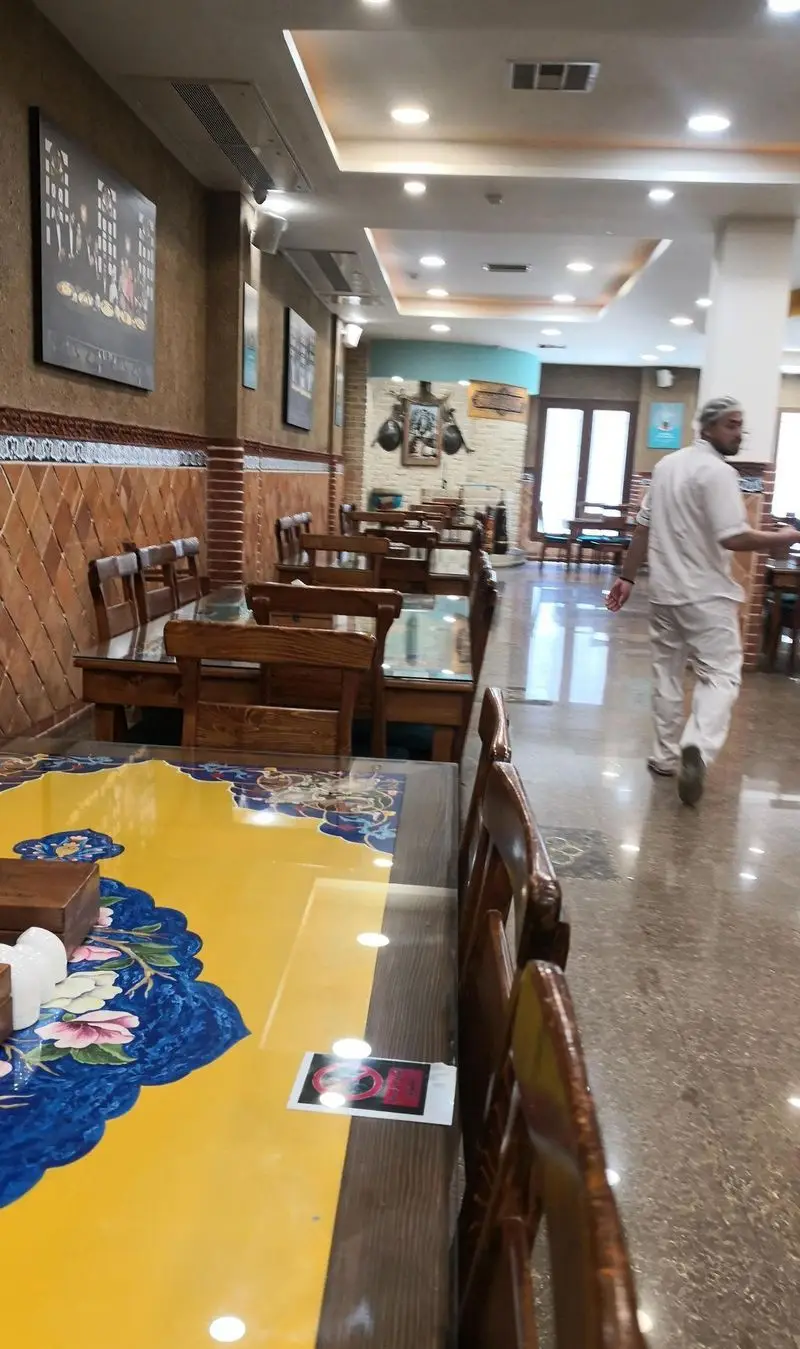 فضای داخلی رستوران مرشد سعادت آباد، با چیدمان میز و صندلی‌های چوبی، دکوراسیون سنتی و مدرن، محیطی دلنشین و آماده پذیرایی.