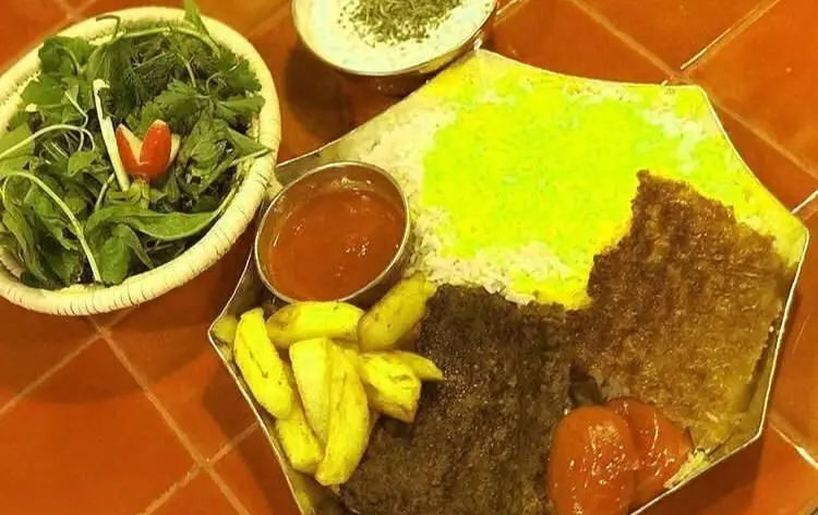 بشقابی پر از کباب‌های لذیذ رستوران رافی، برنج زعفرانی و ته دیگ، سبزی خوردن تازه، سیب زمینی و ماست و خیار. طعم اصیل ایرانی.