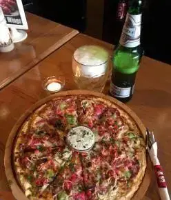 تصویری جذاب از پیتزای بزرگ و پرملات رستوران منهتن گریل با دیپ مخصوص، به همراه نوشیدنی خنک در فضایی دنج و مناسب برای گذراندن اوقاتی دلپذیر.