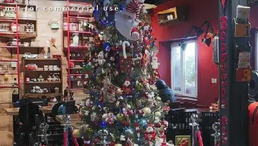 فضای داخلی جذاب رستوران منهتن گریل با درخت کریسمس باشکوه و تزئینات جشن. دکوراسیون خاص با قفسه‌های چوبی و دیوار قرمز جلوه‌ای دلنشین دارد.