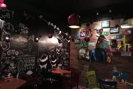 دکوراسیون داخلی جذاب رستوران منهتن گریل با دیوار تخته سیاه و نقاشی‌های خاص، دیوار آجری با المان‌های ورزشی و نورپردازی دلنشین.