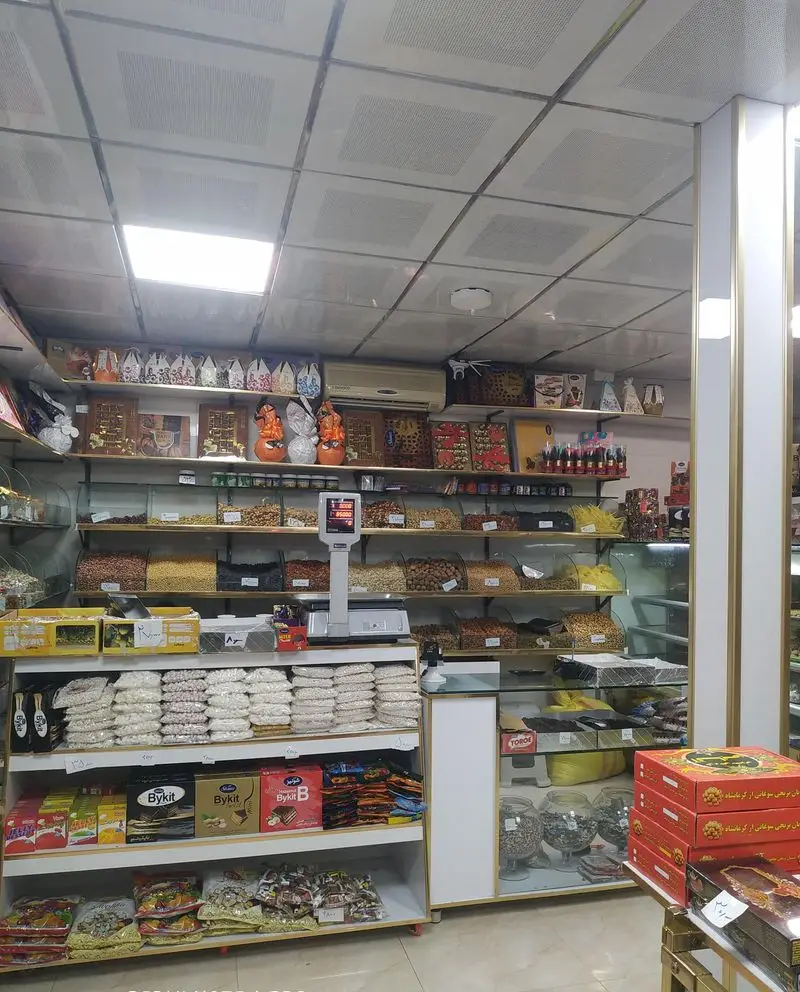 فضای داخلی قنادی گل (مجید) با قفسه‌های گسترده آجیل مرغوب، خشکبار، شیرینی، شکلات و سوغات سوهان کرمانشاه.