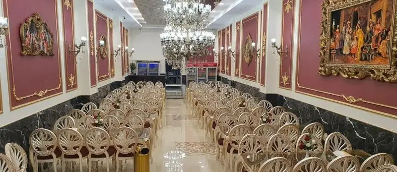 سالن پذیرایی لوکس و مجلل رستوران گل نرگس با چیدمان صندلی‌های سفید، لوسترهای کریستالی و دکوراسیون کلاسیک مناسب انواع مراسم و مهمانی.