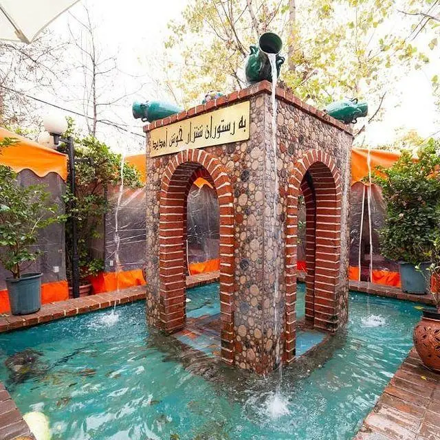 فضای سنتی و دلنشین رستوران شنزار با آبنمای سنگی و آجری، حوض فیروزه‌ای و محیطی آرامش‌بخش و زیبا در فضای باز.