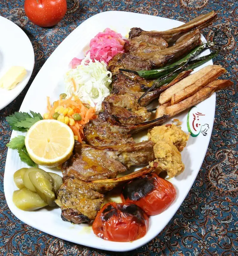 دنده کباب لذیذ رستوران شنزار با سیب‌زمینی سرخ‌کرده، گوجه کبابی، سالاد فصل، خیارشور و مخلفات دیگر. غذایی عالی و خاطره‌انگیز.