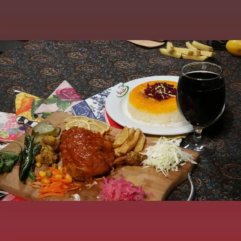 نمایی از چلو مرغ خوشمزه، ته دیگ زعفرانی و مخلفات تازه در رستوران شنزار؛ بهترین انتخاب برای غذای سنتی ایرانی.