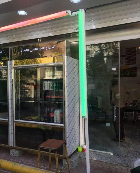 نمای ورودی کباب سرای محسن، شامل پیشخوان استیل براق، یخچال نمایش نوشیدنی و تابلوهای نورانی قرمز و سبز برای جذب مشتری.