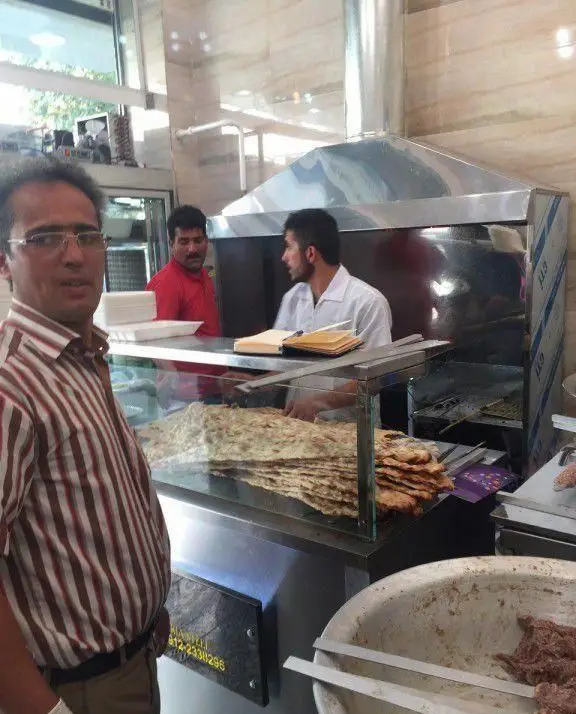 تصویری از محیط داخلی کباب سرای محسن، جایی که پرسنل ماهر در حال تهیه و پخت کباب‌های لذیذ و نان تازه هستند.