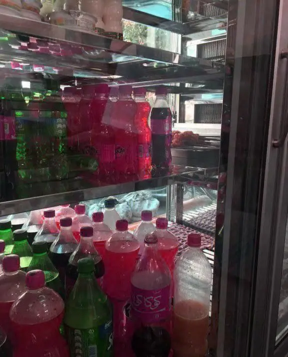 انواع نوشیدنی های خنک و تازه در یخچال کباب سرای محسن، شامل نوشابه های قرمز و سبز، آماده سرو در کنار غذاهای خوشمزه.