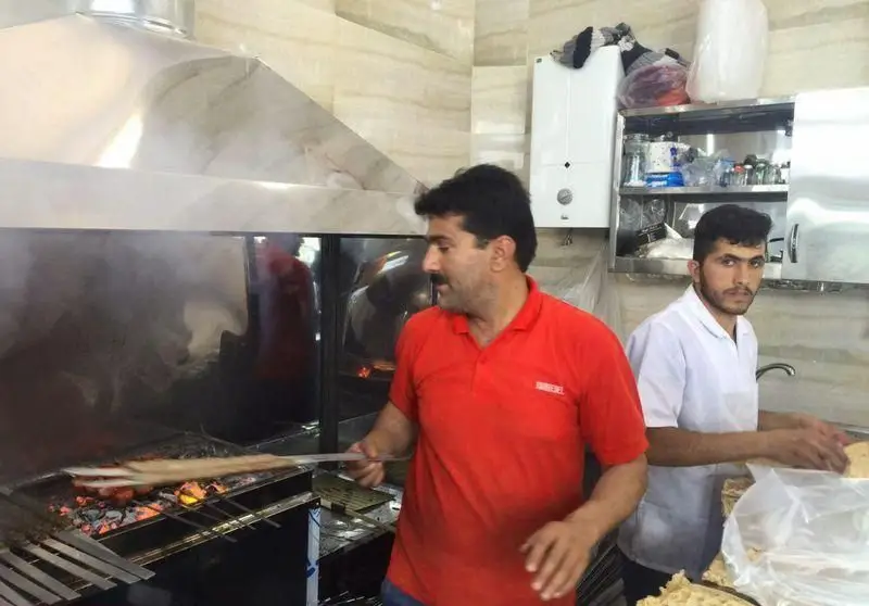 تصویری از آشپز ماهر کباب سرای محسن در حال آماده سازی و پخت کباب داغ بر روی منقل ذغالی، ارائه بهترین طعم کباب اصیل ایرانی