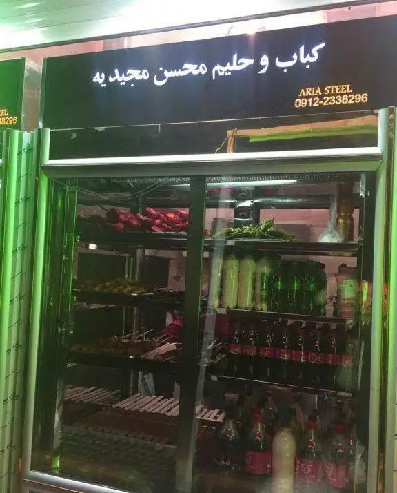 نمای بیرونی کباب و حلیم سرای محسن در منطقه مجیدیه تهران با یخچال ویترینی حاوی کباب‌های لذیذ و نوشیدنی‌های خنک.