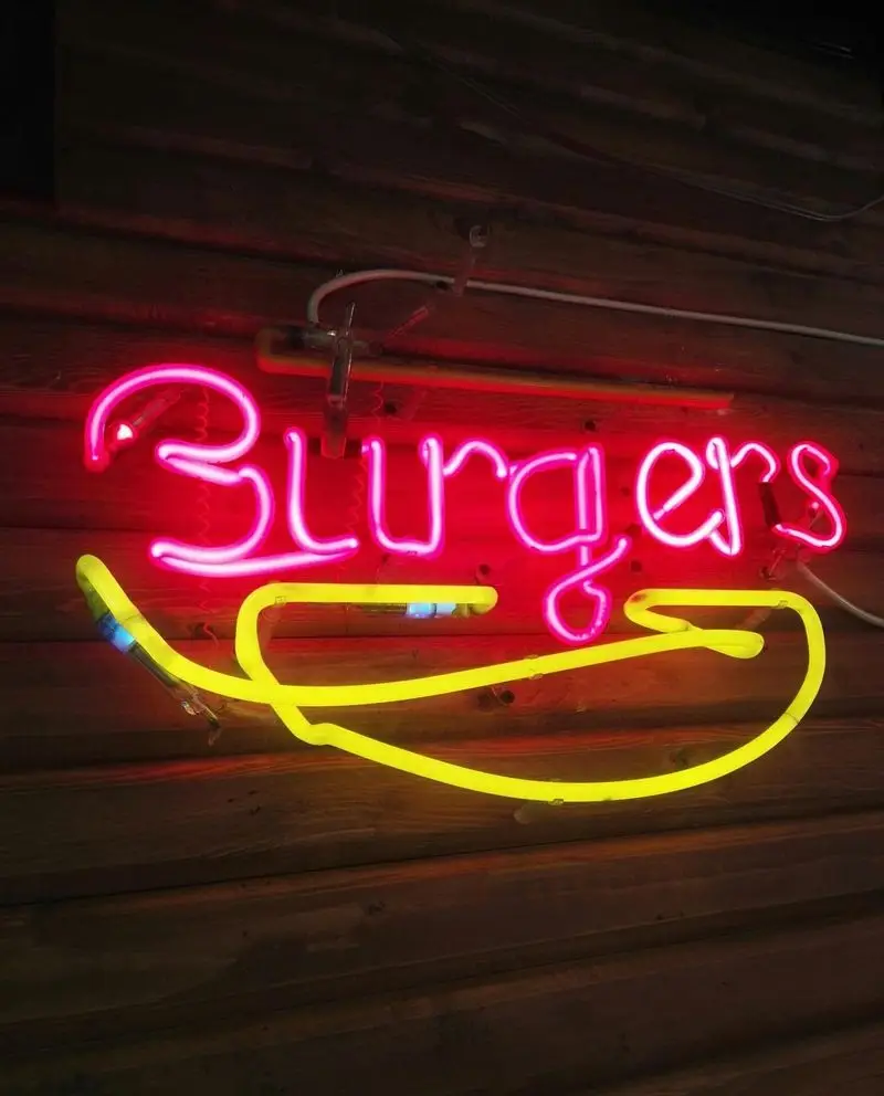 تابلوی نئون درخشان "Burgers" به رنگ قرمز و طرح ساندویچ زرد، جذب مشتری در فست فود وارطان لند شیراز جنوبی.