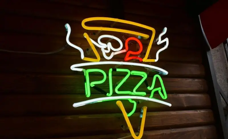تابلو نئون جذاب و پرنور کسب و کار پیتزا وارطان لند (شیراز جنوبی)، با طرح پیتزا و نام "PIZZA" به رنگ سبز روشن.