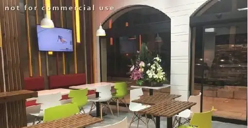 فضای داخلی مدرن و جذاب فست فود سیتادو با دکوراسیون چوبی، مبلمان راحت، میز و صندلی‌های سفید و سبز لیمویی و تلویزیون دیواری