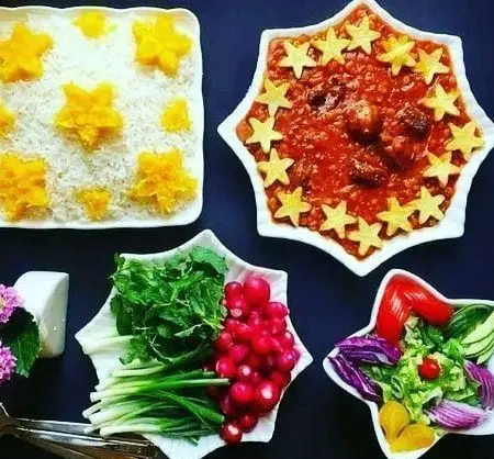 میز غذای مجلسی رستوران خاتون‌ها شامل چلو با تزئینات ستاره‌ای، خورش قیمه با دیزاین خاص، سبزی خوردن و سالاد شیک ایرانی. هنر آشپزی سنتی.