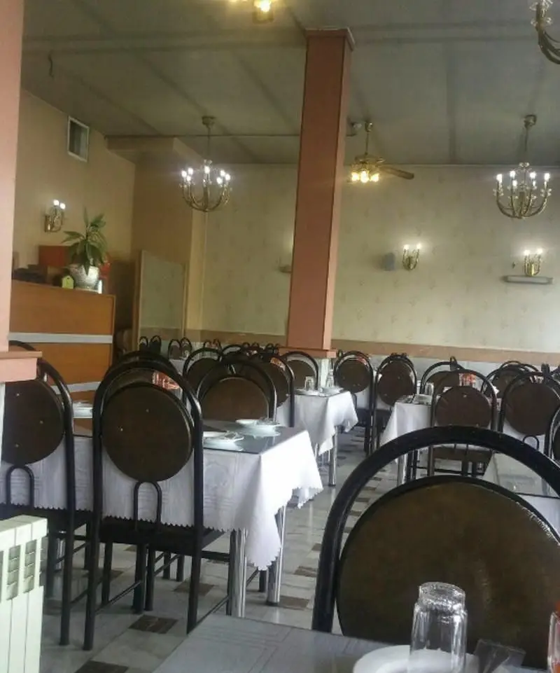 فضای داخلی رستوران ایرانی اقدسیه با میز و صندلی چیدمان شده، لوسترهای کلاسیک و دیوارهای طرح‌دار، آماده پذیرایی از مشتریان.