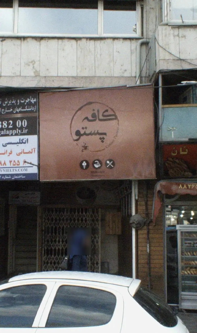 تصویری از نمای بیرونی کافه پستو، کافه ای دنج با تابلو و لوگوی خاص خود و آیکون های قهوه و بستنی در کنار پیاده رو شهر