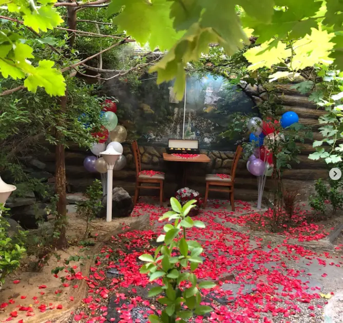 فضای عاشقانه کافه پستو با دیزاین خاص: میز دونفره، رزهای قرمز، بادکنک‌های رنگی، مناسب قرار و جشن در فضای باز دلنشین.