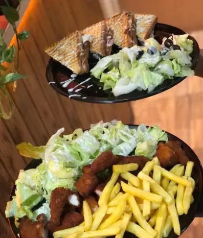 غذاهای خوشمزه کافه پستو شامل ساندویچ تست، سالاد تازه، سیب زمینی سرخ کرده و مرغ سوخاری لذیذ مناسب برای وعده شما.