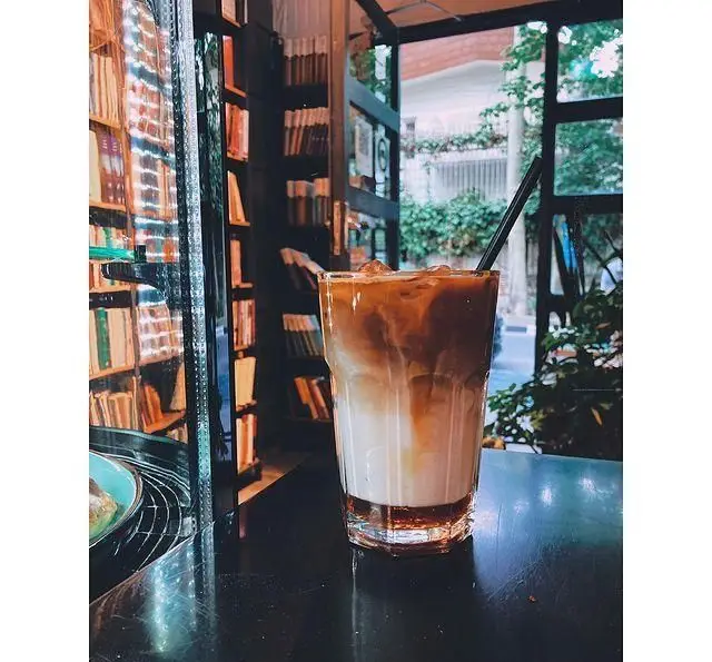 کافه کتاب آینده، یک لاته یخی چندلایه جذاب در محیطی دنج و کتابخانه‌ای. فضایی عالی برای مطالعه و نوشیدن قهوه.