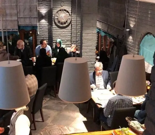 فضای داخلی رستوران آمولای با دکوراسیون جذاب آجری، نورپردازی گرم و مشتریانی در حال لذت بردن از غذا و محیط دلپذیر.