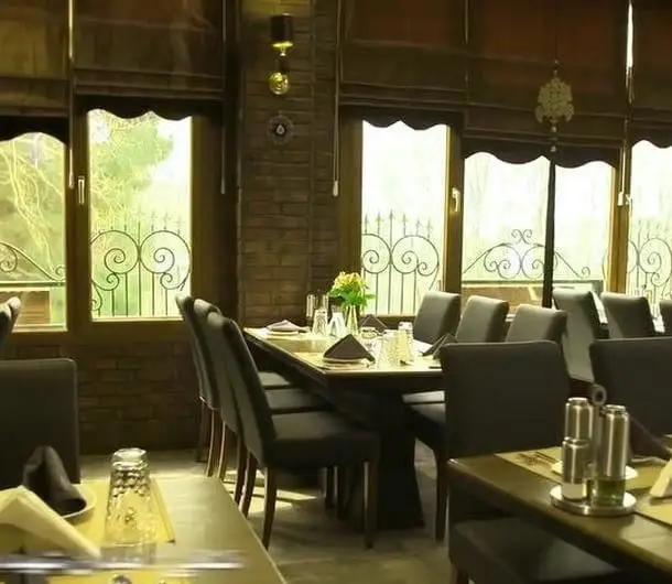 دکوراسیون شیک و فضای آرامش‌بخش رستوران آمولای، با میزهای آماده پذیرایی، صندلی‌های راحت و منظره زیبای بیرون از پنجره‌ها.