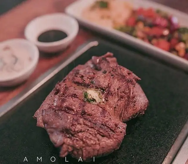 استیک لذیذ رستوران آمولای، سرو شده روی سنگ داغ با کره و سبزیجات معطر، یک تجربه غذایی فوق‌العاده.