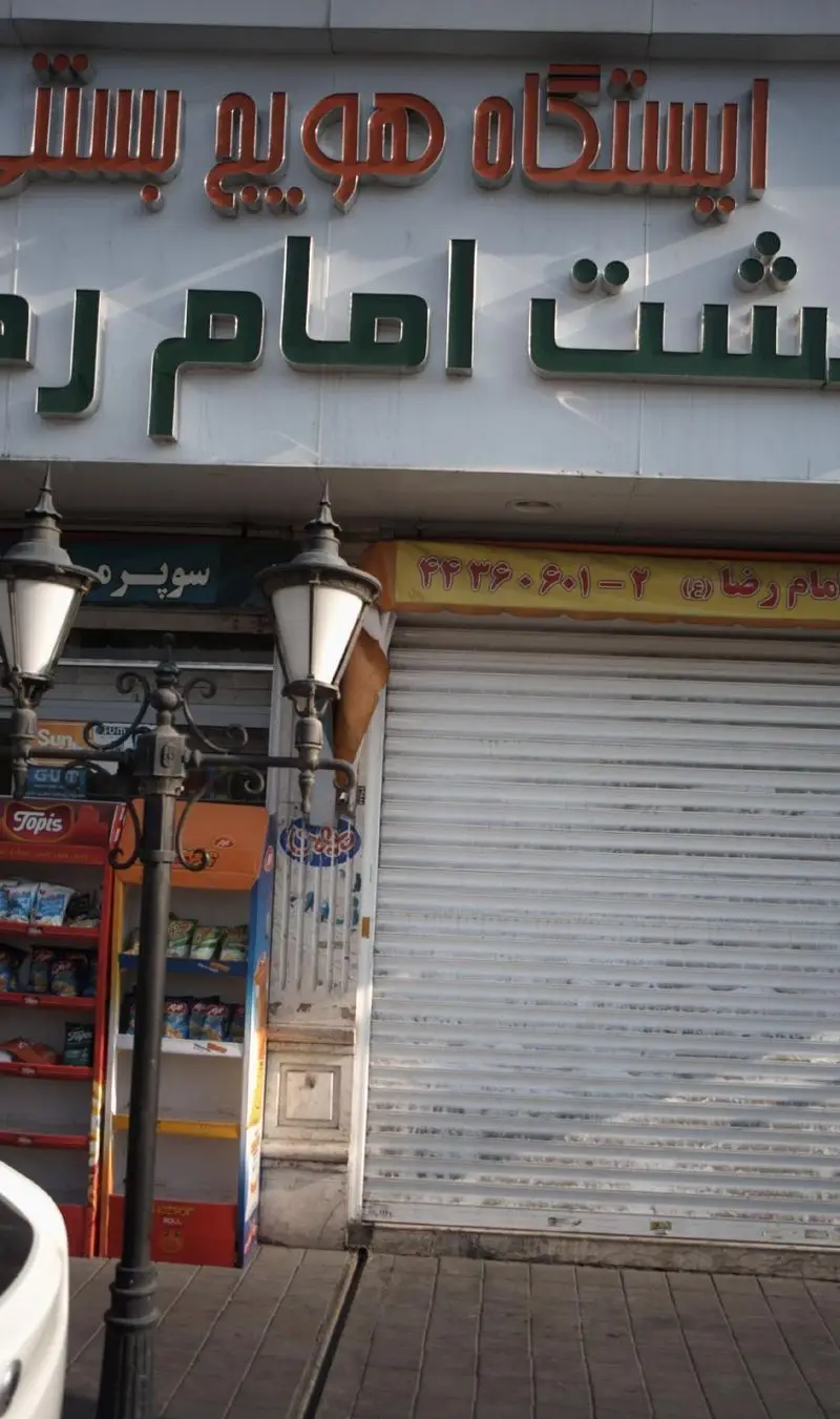 تابلوی مغازه ایستگاه هویج بستنی بهشت امام رضا (ع) با فونت برجسته سبز و نارنجی، نمای بیرونی آبمیوه بستنی فروشی در خیابان.