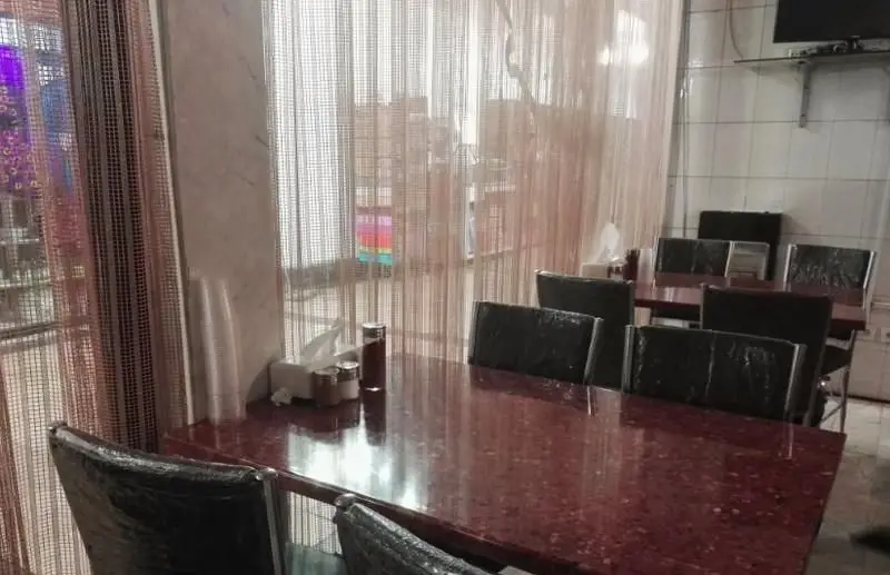 فضای داخلی دنج و تمیز رستوران ایرانی اکبری با میزهای قرمز و صندلی‌های راحت، آماده پذیرایی از میهمانان برای تجربه غذای اصیل ایرانی.