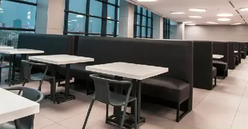 تصویری از فضای داخلی فودکورت چارسو با چیدمان مدرن میز و صندلی‌های سفید و مبلمان‌های نیمکتی مشکی، مناسب برای انواع سلیقه و نشست‌های خانوادگی.