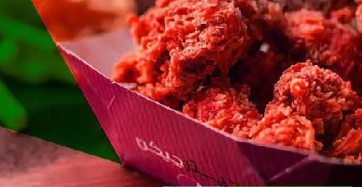 مرغ سوخاری اسپایسی و کریسپی در ظرفی قرمز رنگ، آماده سرو در فودکورت چارسو، انتخابی لذیذ برای دوستداران غذاهای پر هیجان و تند.