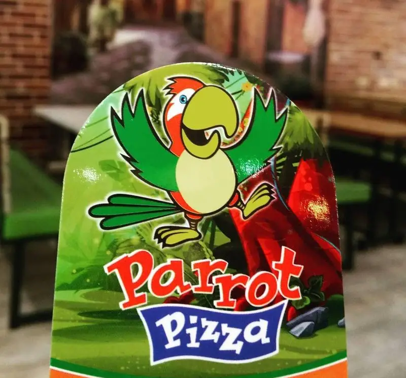 لوگو و طرح تبلیغاتی پیتزا تنوری پاروت، شامل تصویر طوطی رنگارنگ و شاد، نمادی از تازگی و سرزندگی در فست فود و رستوران.