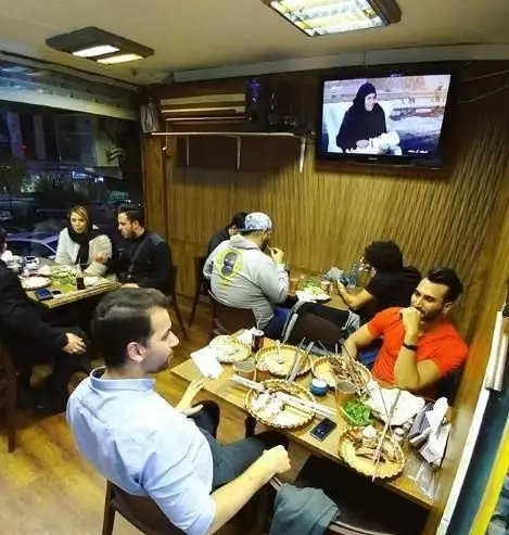 تصویری از مشتریان خوشحال در رستوران آتیش کته کبابی سنتی، در حال سرو کباب و کته‌های تازه و لذیذ در فضایی سنتی و دلپذیر.