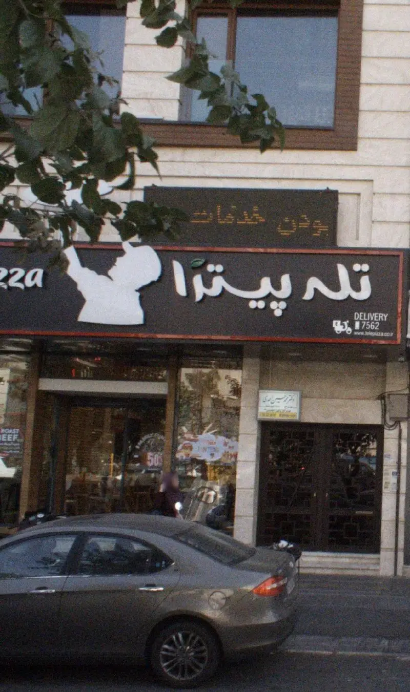 نمای بیرونی شعبه پیروزی تله پیتزا، رستوران فست‌فود با تابلوی روشن، لوگوی مشتری و اطلاعات دلیوری برای سفارش آنلاین.