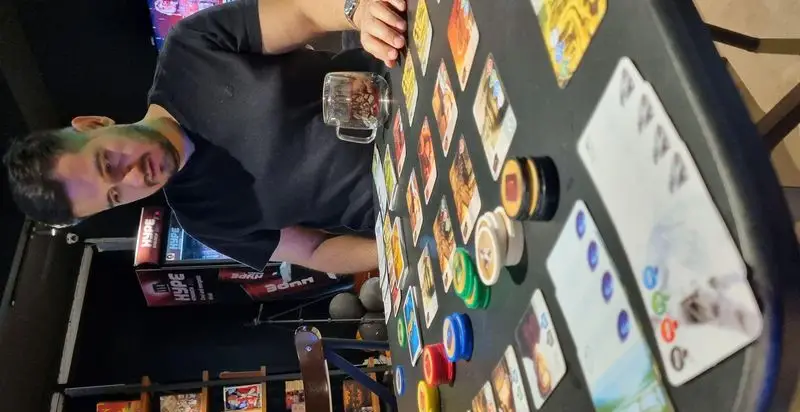 مشتری در کافه گیم استرونات مشغول بازی رومیزی با کارت و ژتون. فضایی دلنشین برای سرگرمی و تفریح علاقه‌مندان به بازی.