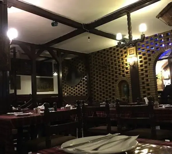 تصویری از فضای داخلی دلنشین و سنتی رستوران پیتزا پنتری با دکوراسیون چوبی و آجری، میز و صندلی‌های شیک برای تجربه‌ای لذت‌بخش.