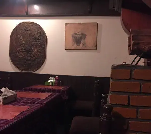 نمای داخلی رستوران پیتزا پنتری با دکوراسیون گرم و دلنشین، شامل میزهای چوبی، صندلی‌های راحت و آثار هنری روی دیوار.