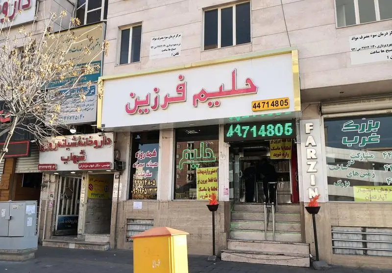 نمای بیرونی رستوران حلیم فرزین با تابلوی بزرگ صورتی و سفید، نمایشگر شماره تماس 44714805 در خیابان اصلی تهران، آماده خدمت رسانی به مشتریان.