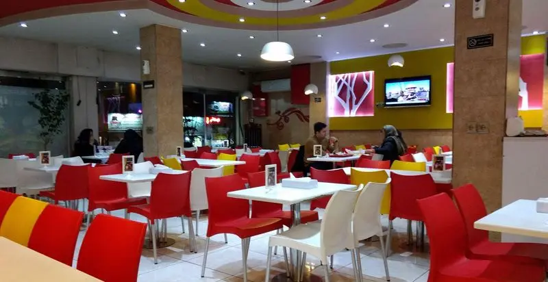 فضای داخلی فست فود زینگر با دکوراسیون مدرن، میز و صندلی‌های سفید، قرمز و زرد، محیطی جذاب و دلپذیر برای مشتریان جهت لذت بردن از غذا.